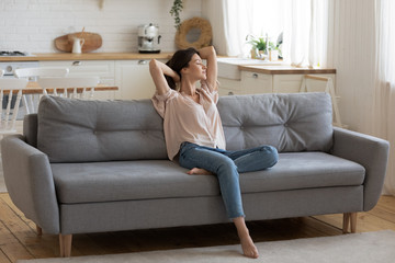 Calm serene young woman relaxing on couch at home