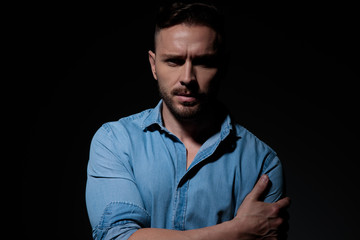 casual man standing and holding arm confident