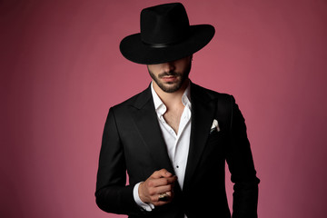 Serious looking man wearing a black suit and hat