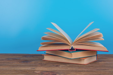 A beautifully open book lies on a wooden table and a blue background. The concept of reading books, training, study, school, education.