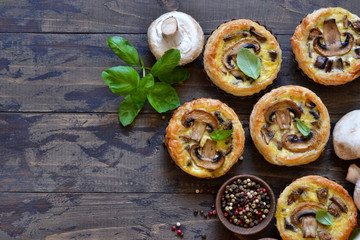 Obraz na płótnie Canvas Tartlets with mushrooms and chicken on a wooden background. View from above.