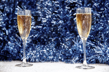 Two beautiful Christmas glasses with splashes and Christmas decorations with bokeh in the foreground, mysterious new year background.