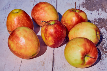 red juicy ripe apples on an old wooden table against the background of autumn nature in the garden, soft selective focus