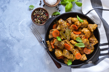 Stew with spices in a pan on a concrete background. View from above.