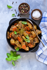 Stew with spices in a pan on a concrete background. View from above.