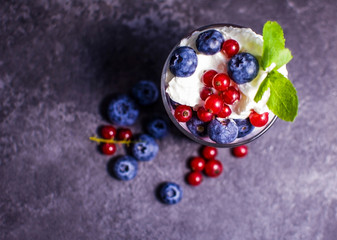 yogurt with currants and blueberries on a dark background