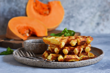 Belgian waffles with pumpkin and chocolate sauce on a concrete background with place for text.