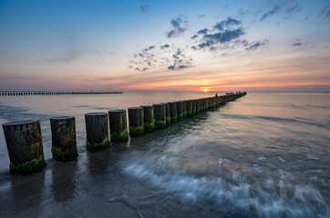Baltic sea seascape at sunset, Poland, wooden breakwater and waves