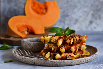 Belgian waffles with pumpkin and chocolate sauce on a concrete background with place for text.