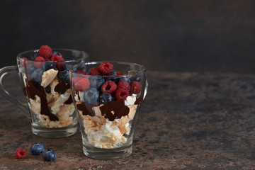Dessert in a glass with chocolate, meringues and berries on a dark background. Close up view.