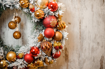 Christmas artificial wreath covered with white snow with golden and red decoration in the left...