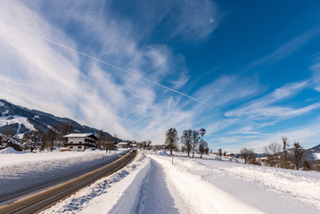 Cloudy blue sky, big snow covered fields and empty road in winter, sunny day. Rohrmoos Untertal, Schladming, Schladming Dachstein, Austria, Europe 