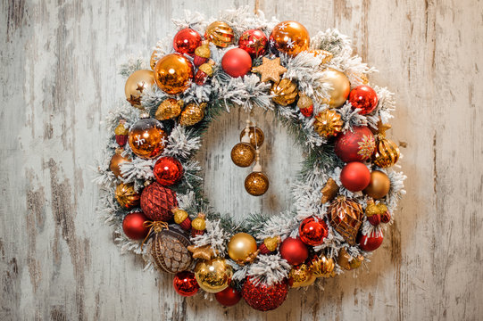 Christmas green artificial wreath covered with white snow with golden and red decoration