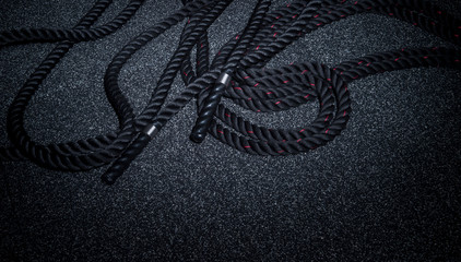 Close up of black battle rope on a gray backgound. Sport and fitness equipment. Functional training