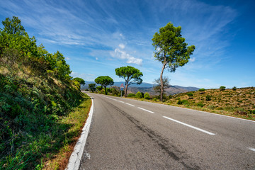 Empty long mountain road to the horizon on a sunny summer day at bright sunset