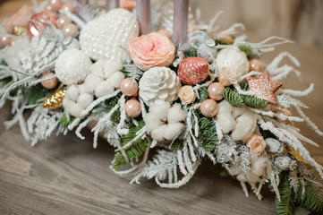 Vase with christmas decor composition of fir-tree branches, candles, flowers and toys