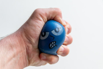 Stressabbau mit Anti-Stressball baut Stress ab durch drücken und quetschen eines blauen Balls mit bösem Gesicht und kräftig gleichzeitig Hand und Unterarmmuskulatur