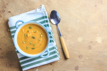 Pumpkin soup and organic pumpkins on rustic table.