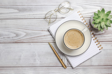 White office workplace desk table with notebook, pen, flower and coffee cup. Top view. Copy space. Flat lay
