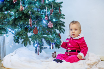 Small boy in Santa suit plays near new-year tree