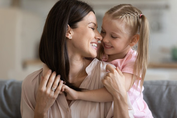 Happy loving mother and little daughter touching noses close up