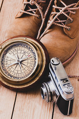  BOOTS WITH COMPASS AND CAMERA OF PHOTOS ON WOODEN TABLE 2 . TRAVELS IN THE WORLD