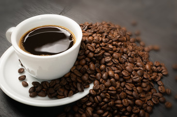 Hot coffee cup and coffee beans on black background top view