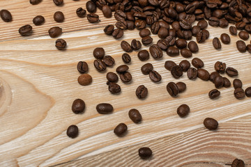 Dark brown whole coffee beans on wood background with copyspace