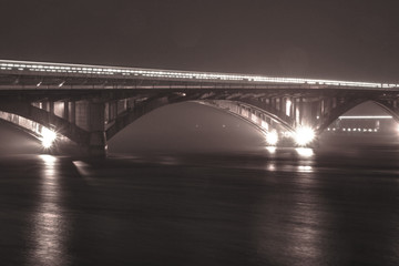 Fototapeta na wymiar Snow and rain in winter against the background of the night old bridge
