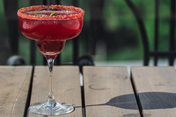 Raspberry Margarita in chilled glass over light background on reflection surface, garnished with fresh mint. Most popular cocktails series.