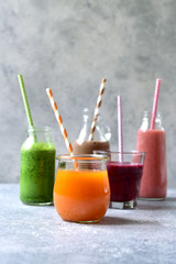 Assortment of colorful smoothies in a bottles with paper straws.