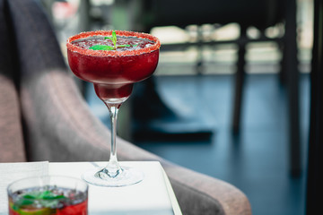Raspberry Margarita in chilled glass over light background on reflection surface, garnished with fresh mint. Most popular cocktails series.