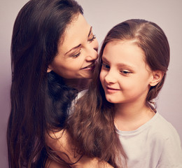 Happy mother and excited joying kid girl hugging with emotional smiling faces on purple background with empty copy space.