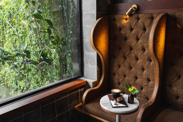 One cup of aroma cappuccino on round marble table, heart shaped latte-art and brown background. Brown sugar and sweets on wooden plate.