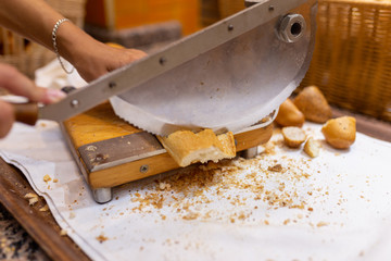 Women's hands cut bread with a bread cutter. The girl cuts French long bread into pieces with a special knife