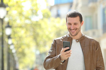 Obraz na płótnie Canvas Happy adult man using a smart phone in the street