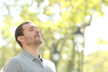Relaxed man breathing deeply fresh air outside in a park