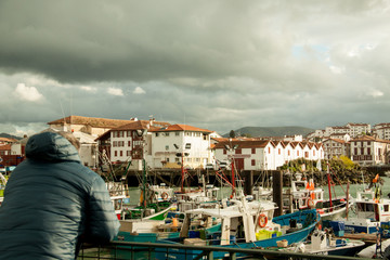 Fototapeta na wymiar Hombre mirando el puerto de Saint Jean de Luz un día de invierno y tormenta