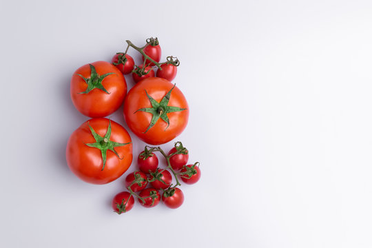 Grape or cherry tomato branch. Pile of red grape and normal tomatoes, isolated on white background, soft light