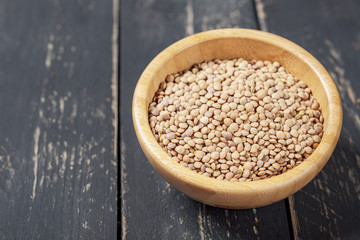 Bowl with green lentils on a white wooden background.