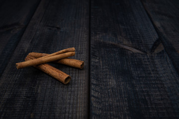 Cinnamon sticks on a dark wooden countertop. The concept of eating and adding spices to dishes. Improving the taste of dishes, sharp expressive taste.
