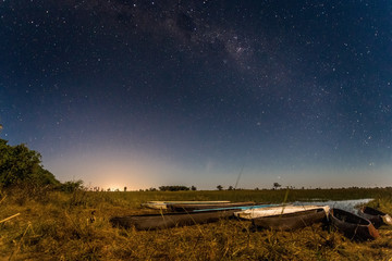 Botswanian local mokoro boats under the starlight sky, on the shore of delta Okavango river,...