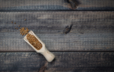 Top view of coriander with a scoop on a dark wooden table top. The concept of eating and adding spices to dishes. Improving the taste of dishes, sharp expressive taste.