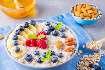 Healthy homemade oatmeal with berries and nuts for breakfast. Oatmeal with fruits, nuts and honey. Oatmeal with blueberries, banana and raspberries