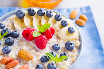 Healthy homemade oatmeal with berries and nuts for breakfast. Oatmeal with fruits, nuts and honey. Oatmeal with blueberries, banana and raspberries