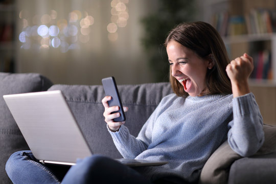 Excited woman using phone and laptop in the night