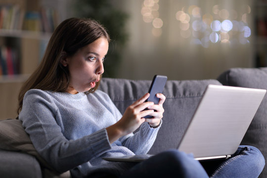 Surprised woman using phone and laptop in the night