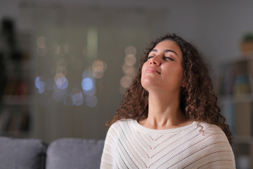 Relaxed woman breathing fresh air in the night at home