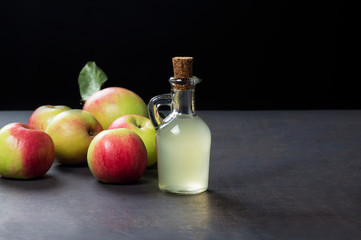 Glass bottle of handmade organic apple cider vinegar made from fermented fresh ripe apples. Healthy organic food, selective focus, space for text