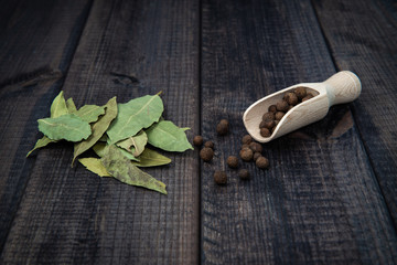 Allspice seeds and bay leaf dark wooden countertop. The concept of eating and adding spices to dishes. Improving the taste of dishes, sharp expressive taste.